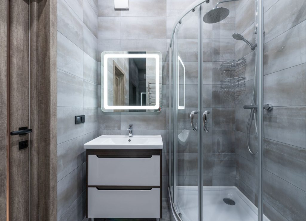 Baño moderno reformado con cabina de ducha y espejo iluminado