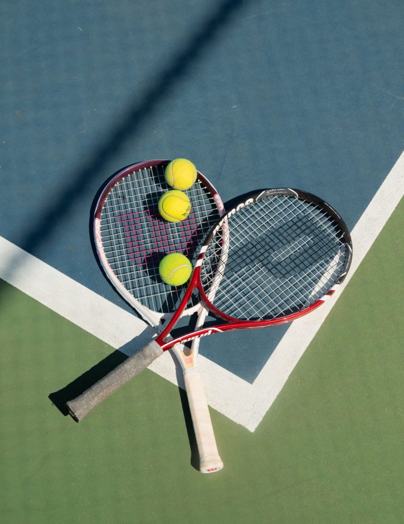 Raquetas y pelotas de tenis sobre una pista, estética tenniscore
