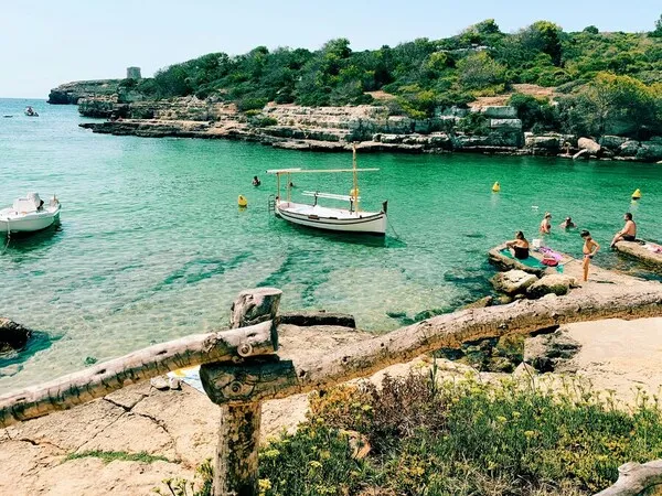 Cala de aguas cristalinas en Menorca con pequeñas embarcaciones