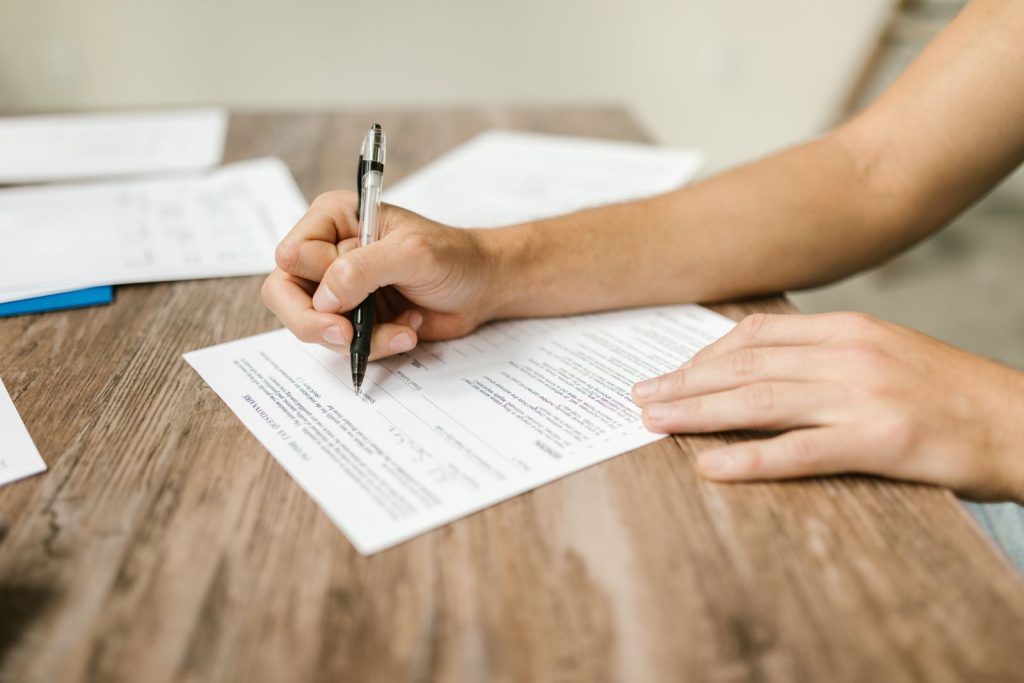 Persona rellenando un formulario en papel con bolígrafo