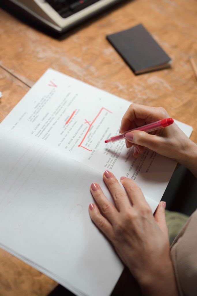 Mano marcando un manuscrito con bolígrafo rojo