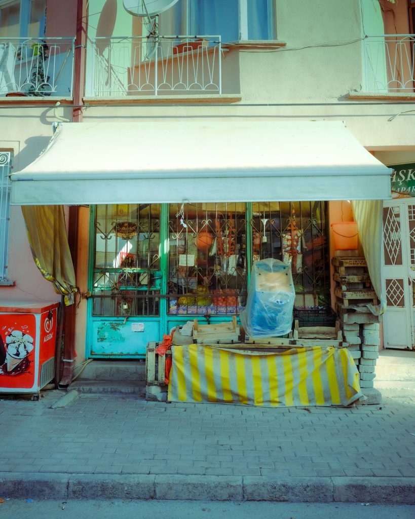 Fachada de un local comercial cerrado con toldo a rayas