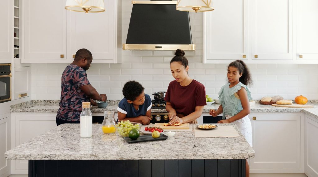 Familia de cuatro personas cocinando juntas en una cocina