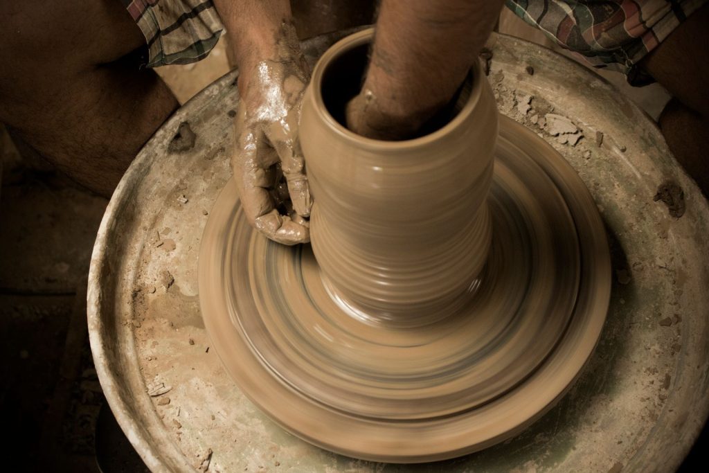 Manos moldeando barro en un torno de alfarero