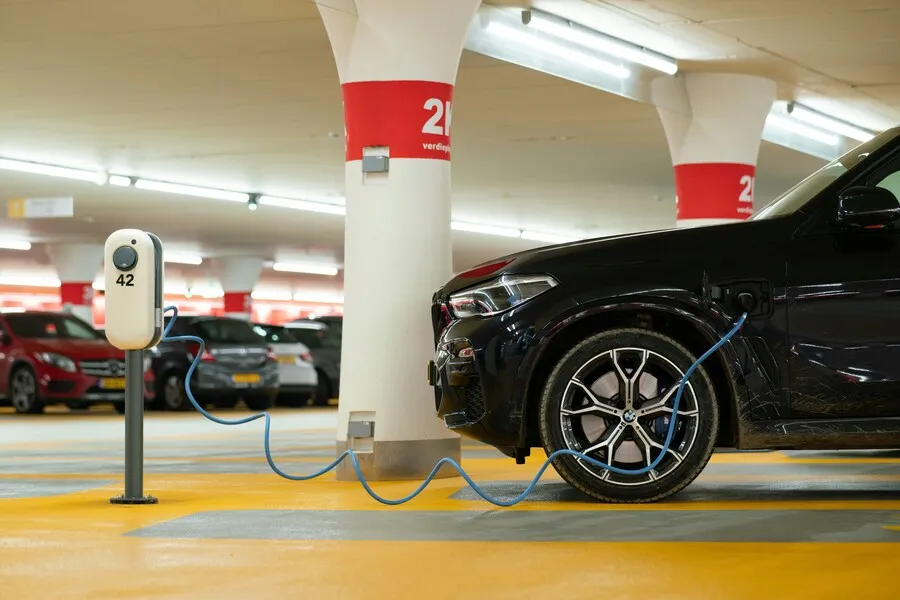 Coche eléctrico conectado a un cargador en un garaje comunitario